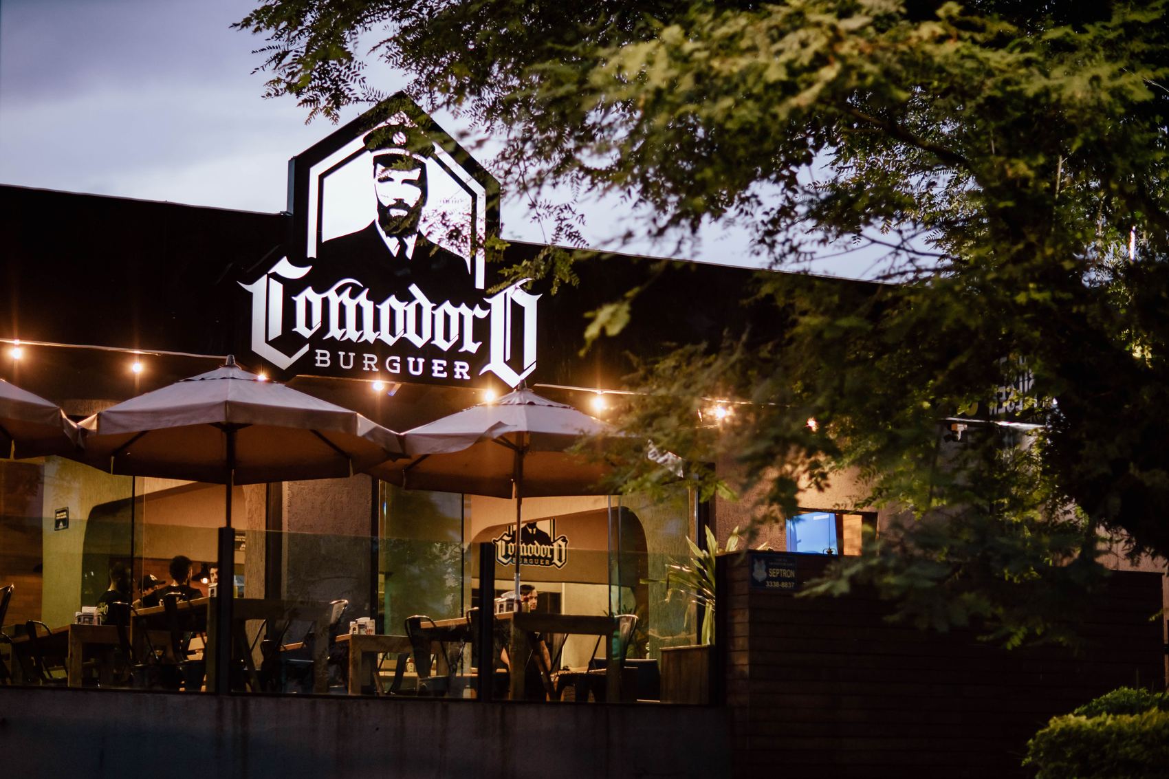 Fachada do Comodoro Burguer iluminada à noite