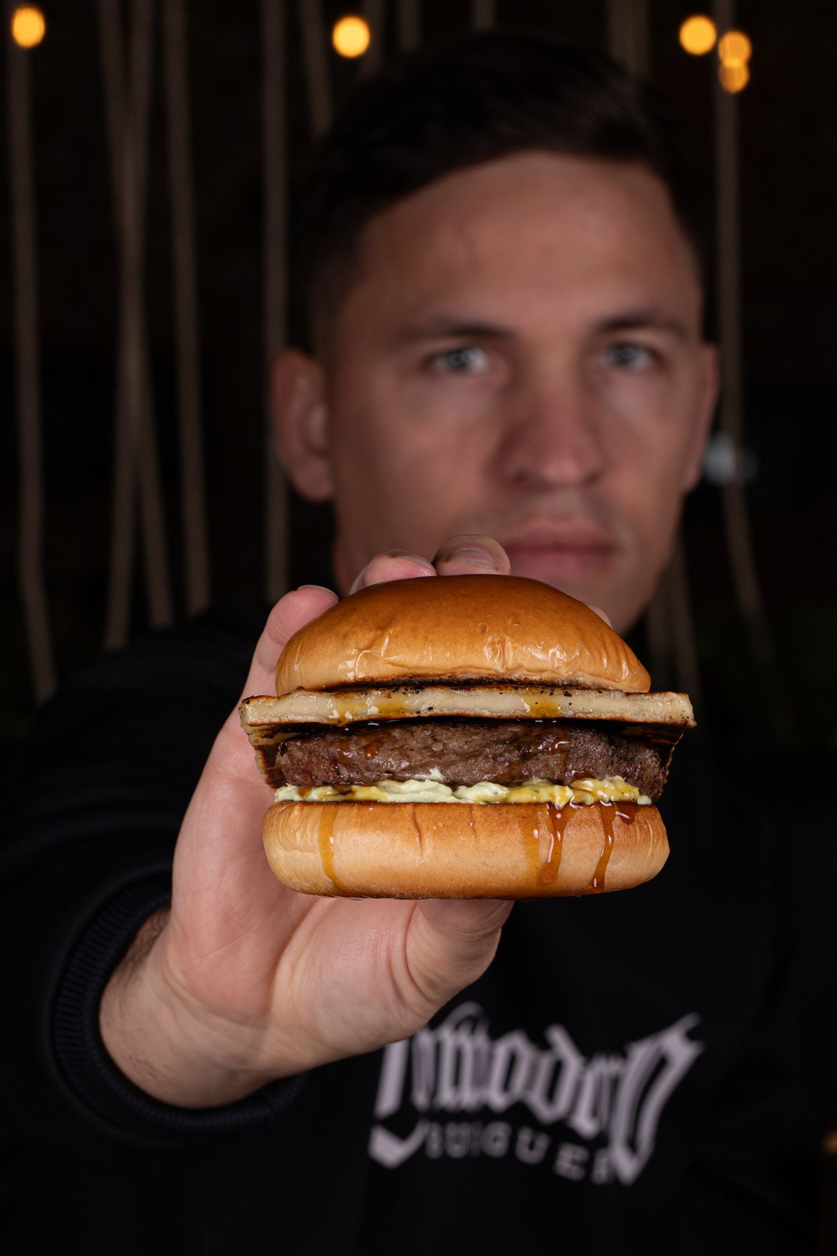 Julio Narloch, dono da Comodoro Burguer, segurando um burguer